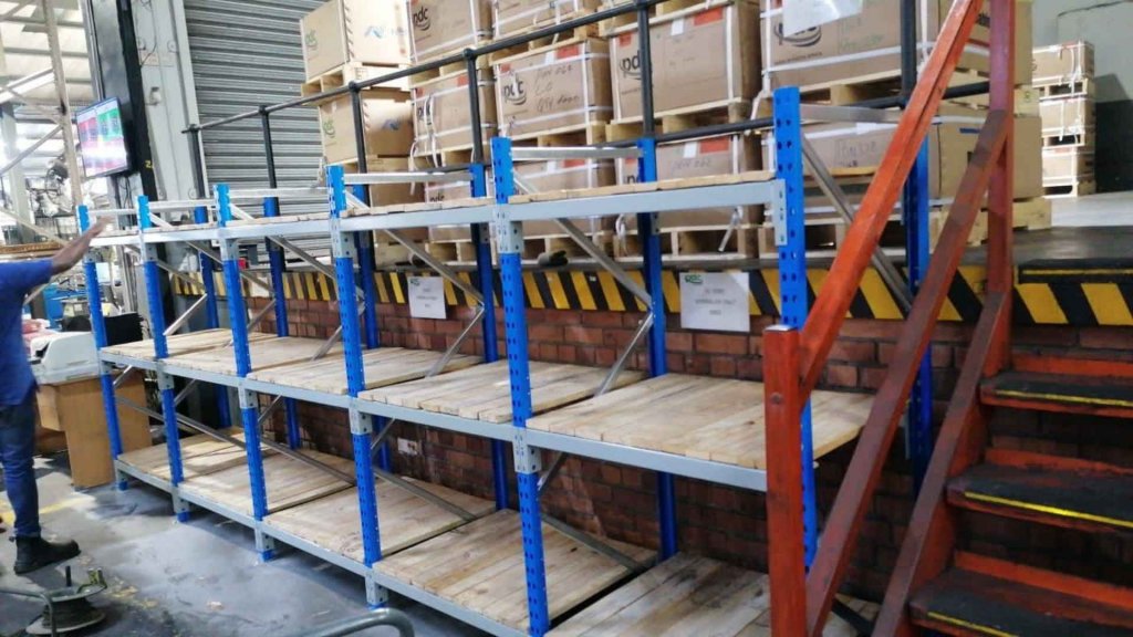 A shelving system with blue and gray supports, filled with wooden pallets and boxes, in a warehouse setting, provided by Duzi Storage Solutions.